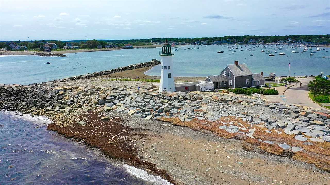 Aerial shot of lighthouse on a jetty in a bay.