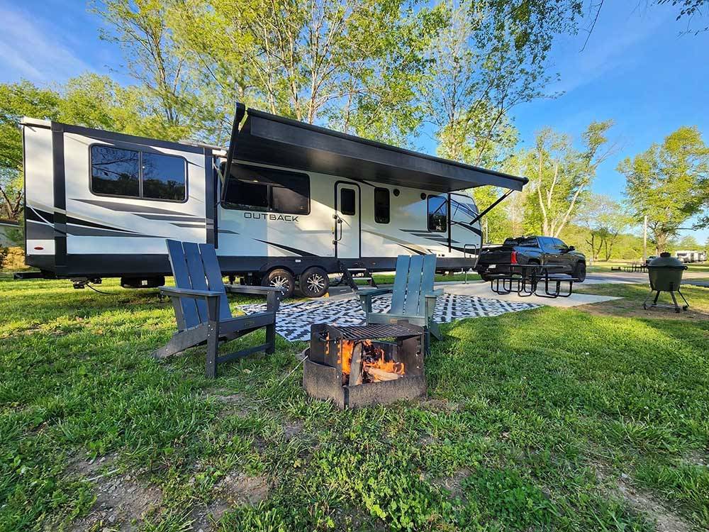 A travel trailer on a grassy campsite with fire.