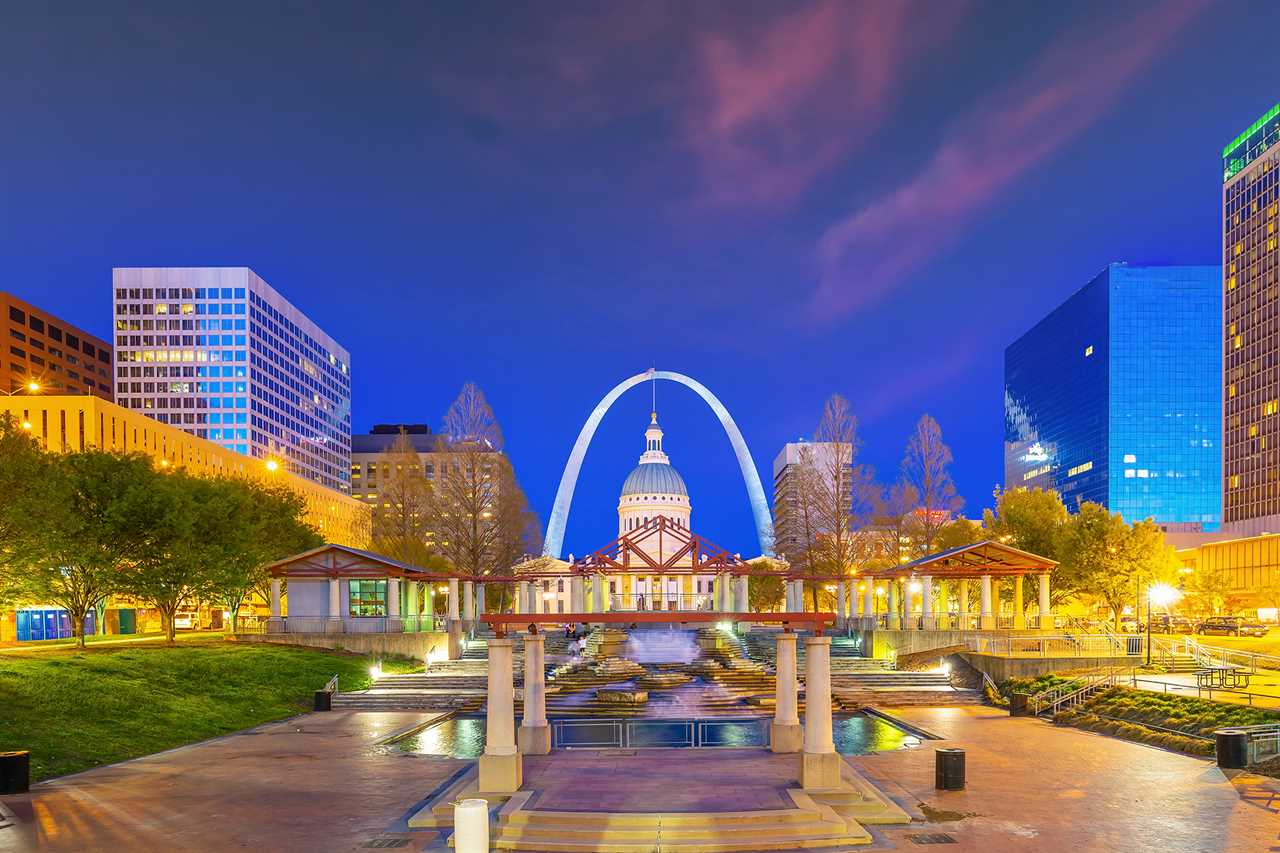 Arch rising over a capitol building in a nighttime cityscape.