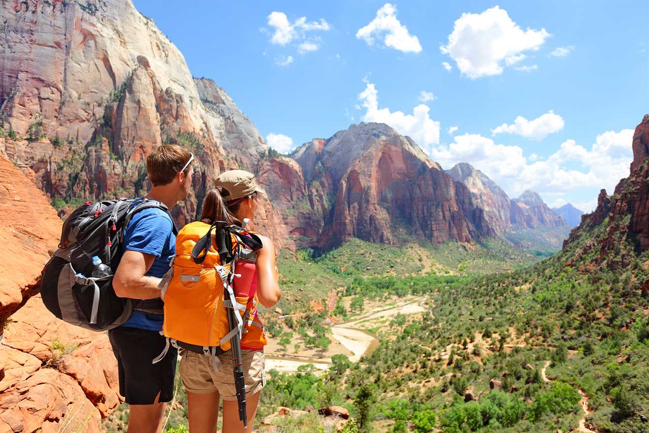 A man and woman look out at a deep valley flanked by tall, sheer mountains.