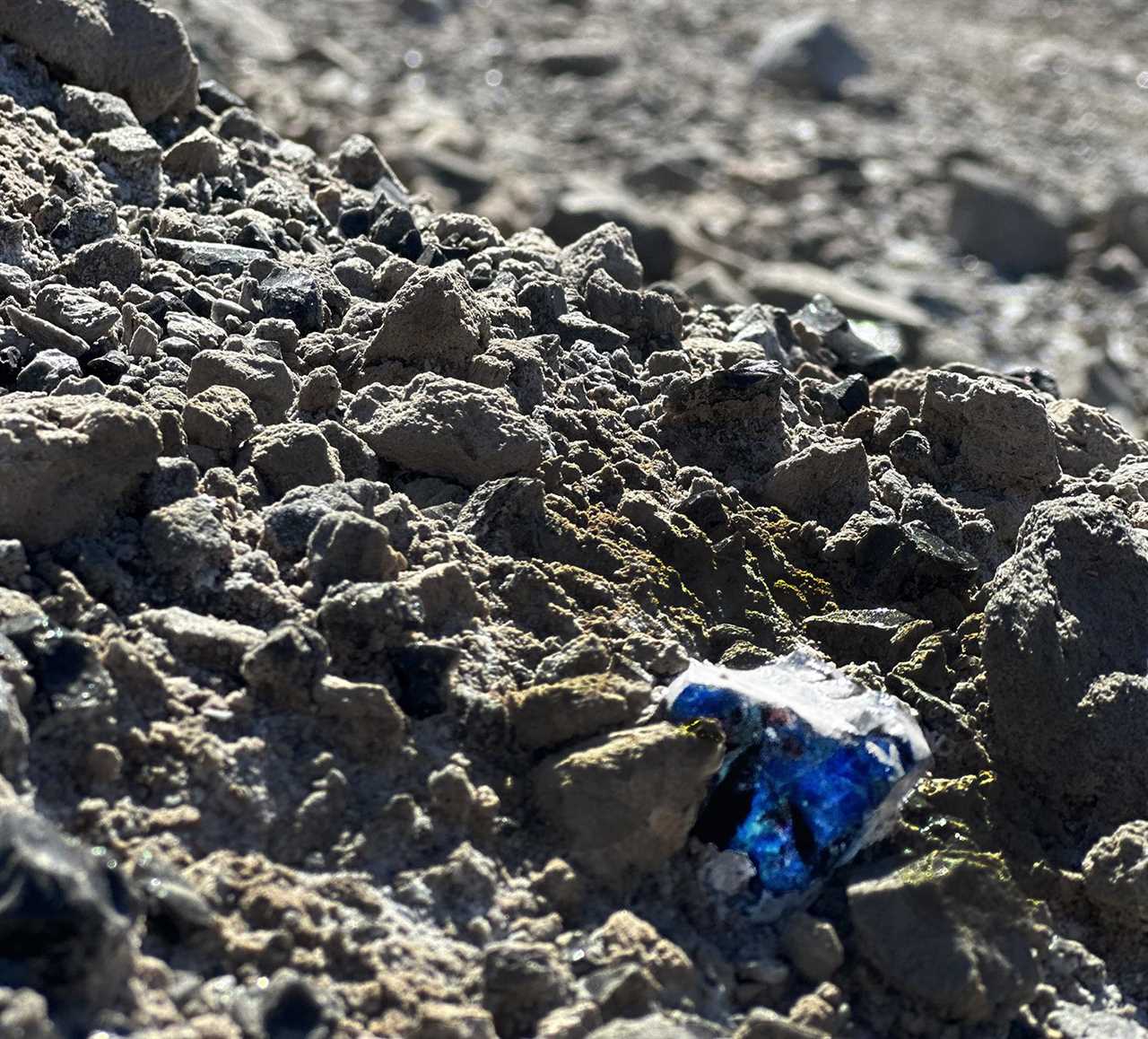 Piece of bright obsidian among other rocks.