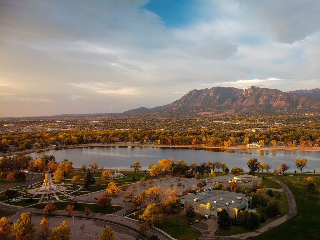 A view from a hill looking towards a lake and the beginning of the rocky mountains in the distance in Colorado Springs at sunset on a hazy day