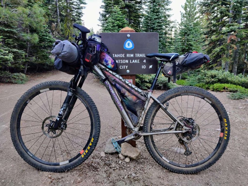 Lightly loaded bikepacking bike leaning against a Tahoe Rim Trail sign