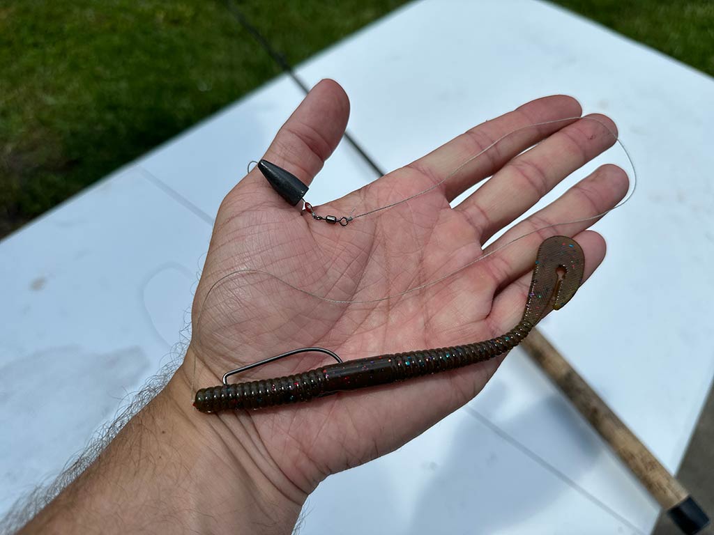 A closeup of a small, black Carolina rig being held on a palm against a whjte table background