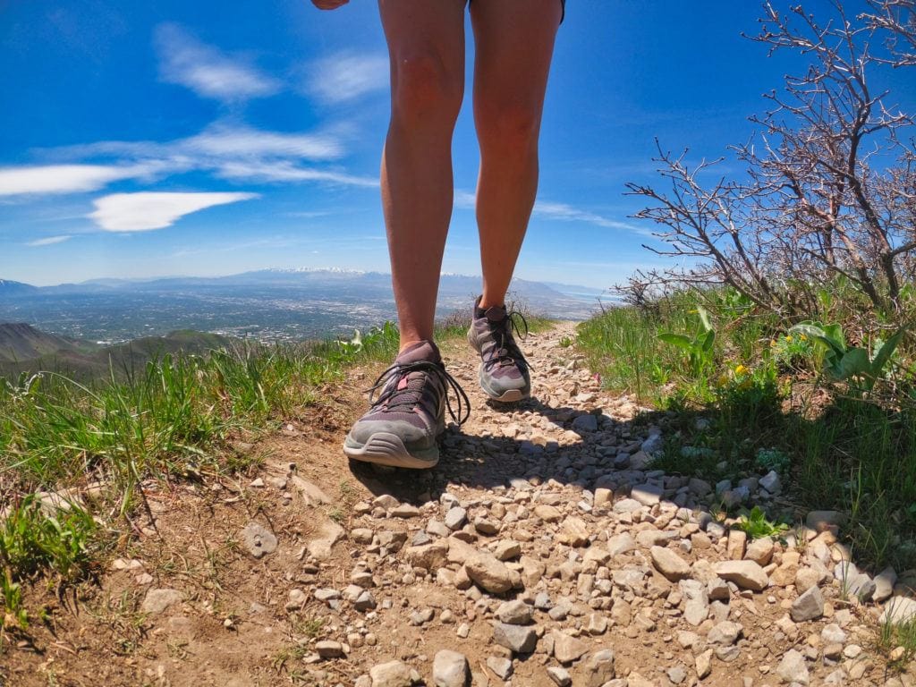 Woman hiking in the foothills on a trail above Salt Lake City. Photo focuses on her shoes