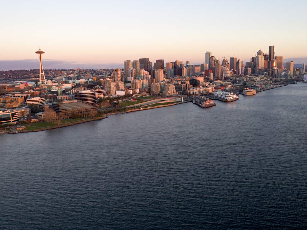An aerial view of the evening skyline of Seattle, as viewed from the Puget Sound waters's, with famous landmarks such as the Space Needle visible.