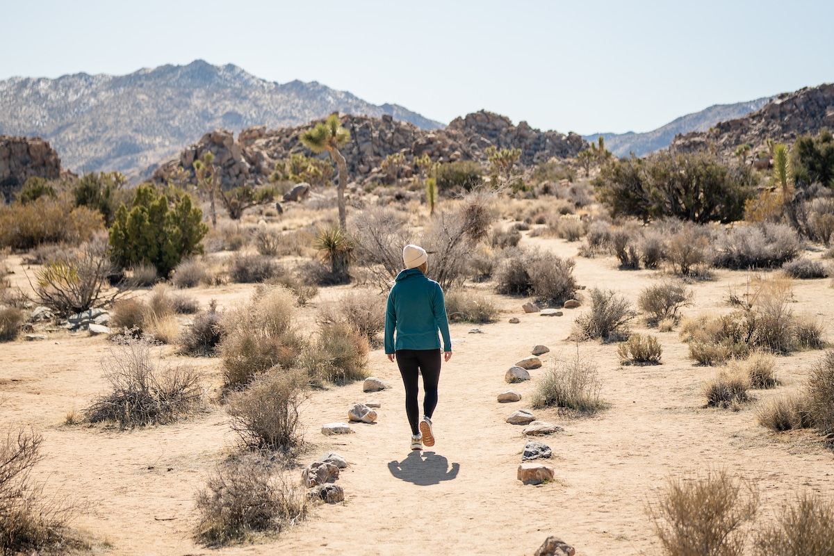 A female hiker wearing the Oboz Cottonwood mid waterproof hiking boots in the color Drizzle on a trail in Joshua Tree National Park