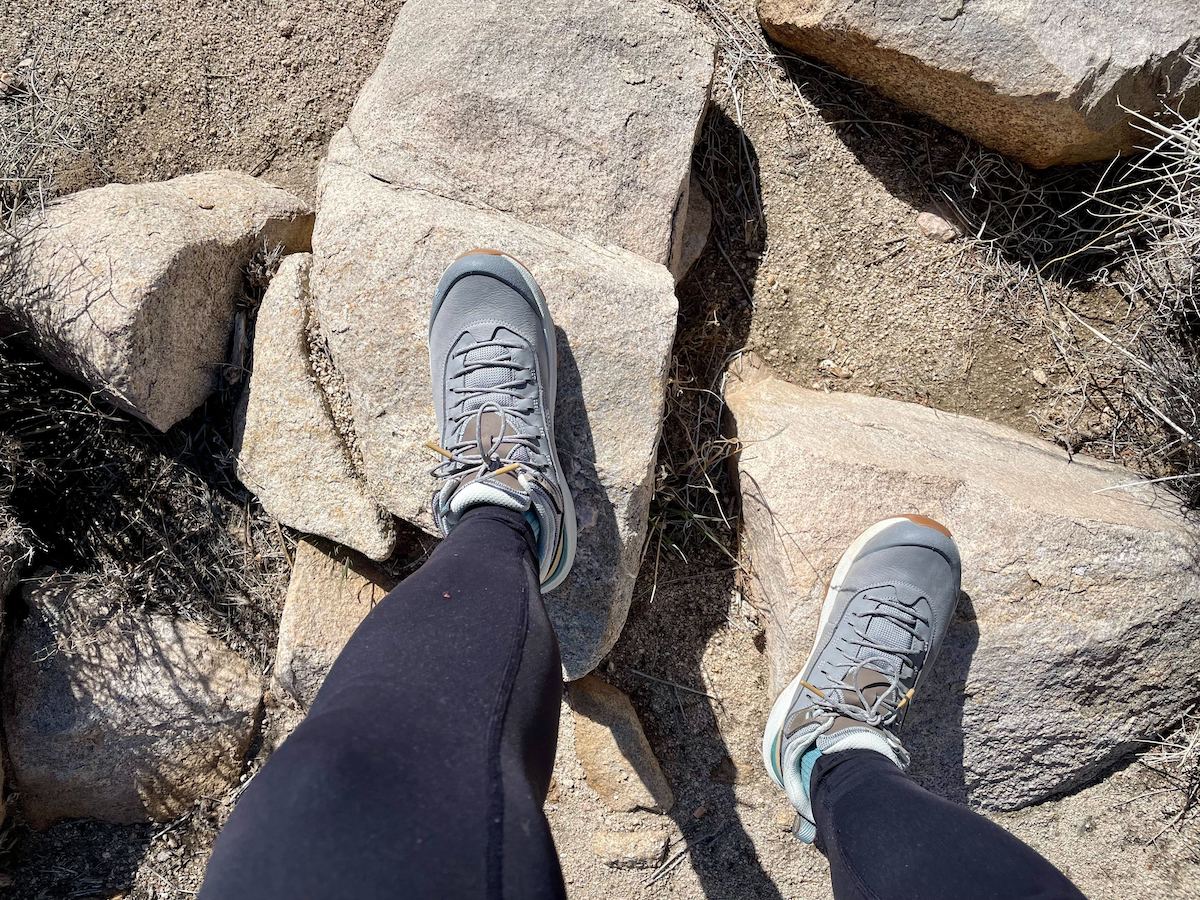 A female hiker wearing the Oboz Cottonwood mid waterproof hiking boots in the color Drizzle on a trail in Joshua Tree National Park