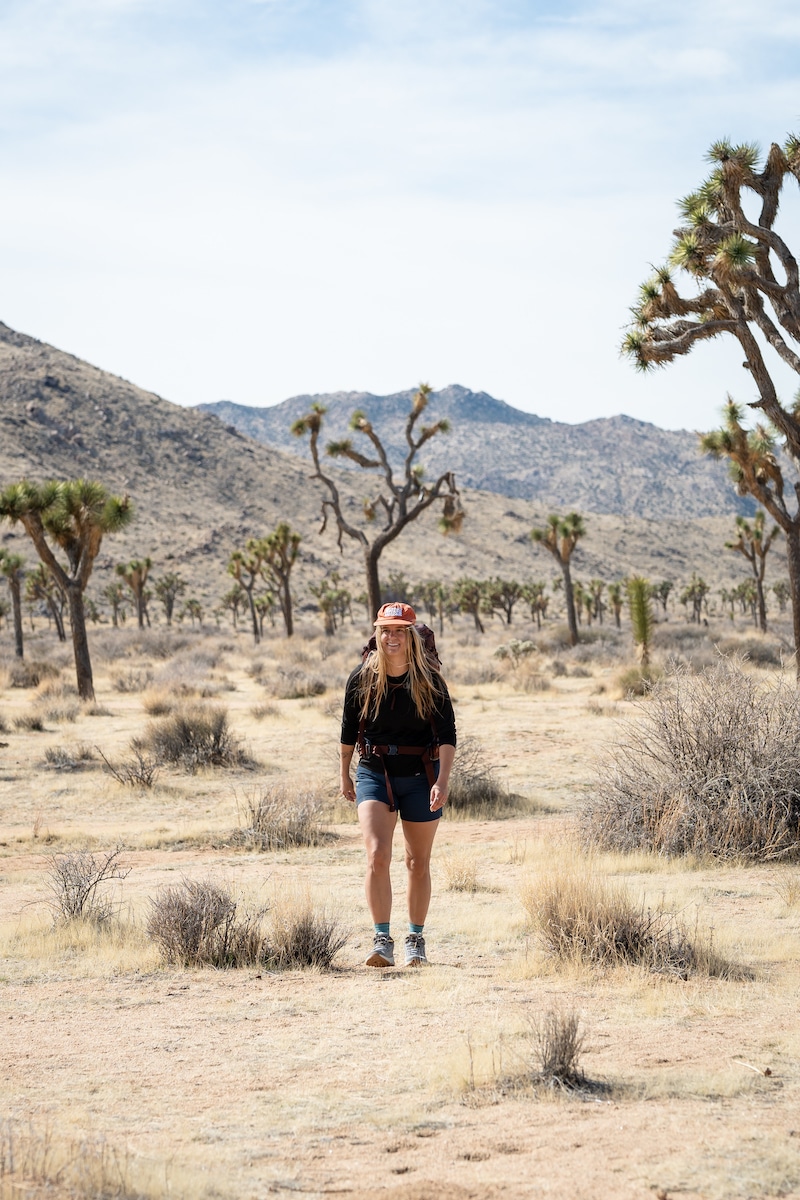 A woman backpacking while wearing shorts and the Oboz Cottonwood mid waterproof hiking boots in the color Drizzle on a trail in Joshua Tree National Park