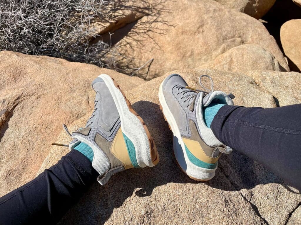 A female hiker wearing the Oboz Cottonwood mid waterproof hiking boots in the color Drizzle on a trail in Joshua Tree National Park