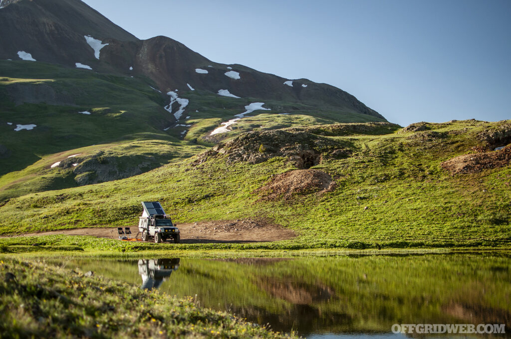 Photo of a 70-Series Toyota Land Cruiser driving next to an alpine lake.