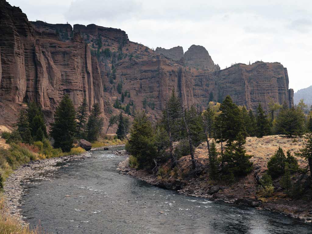 A photo of the North Fork Shoshone River near Cody, Wyoming, with stunning rocky cliffs towering over the left side of the river.
