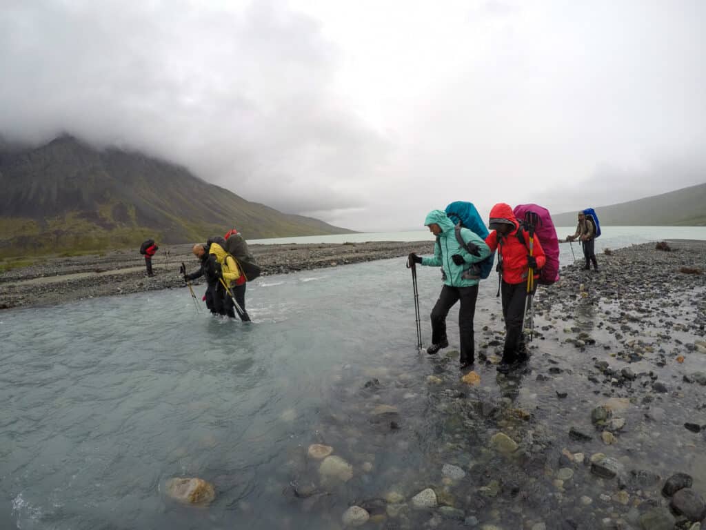 Group of people crossing a river with backpacking packs on