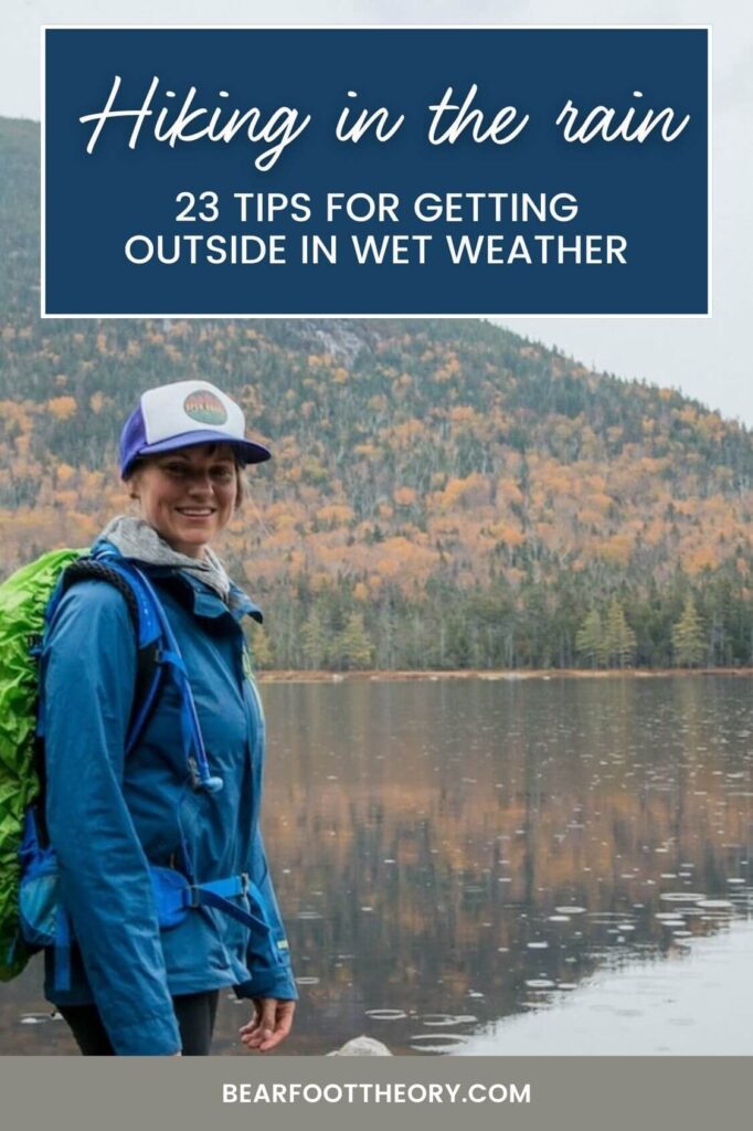 Pinnable image of woman standing next to lake during fall foliage season. Text reads "Hiking in the rain: 23 tips for getting outside in wet weather"