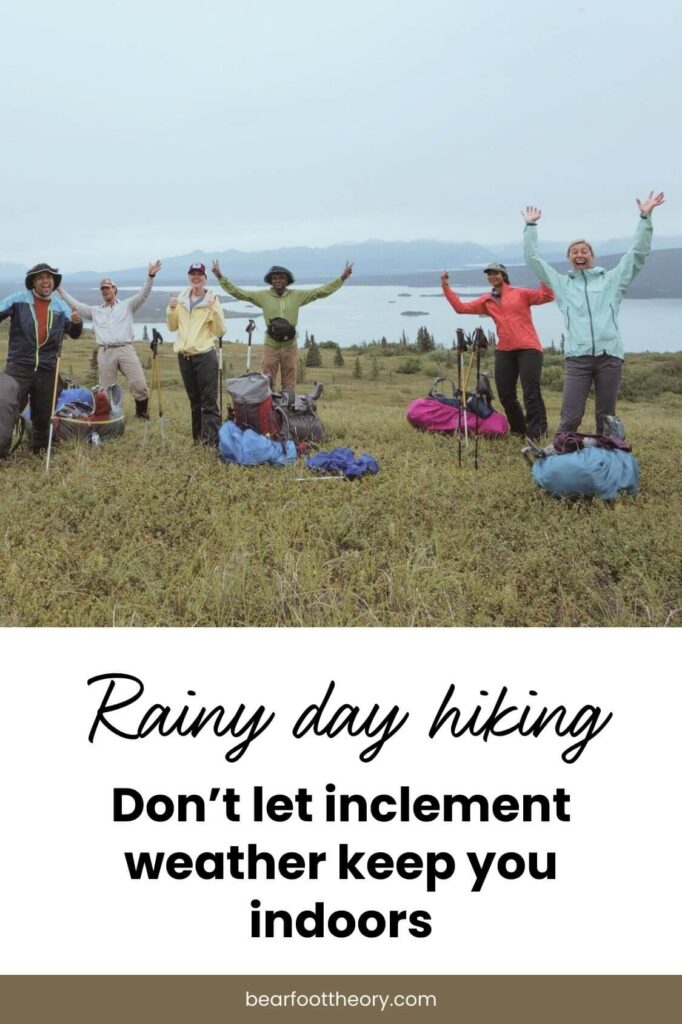 Pinnable image of group of backpackers next to lake with their arms raised for photo. Text reads "Rainy day hiking: Don't let inclement weather keep you indoors"