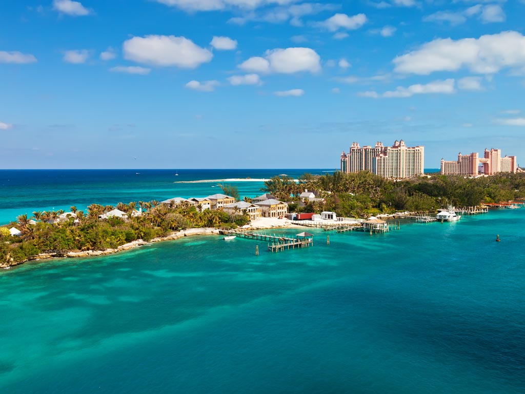 An aerial view of Paradise Island that's found right across from Nassau, with the Atlantis Resort's buildings visible on the island, while beautiful ocean waters surround it.
