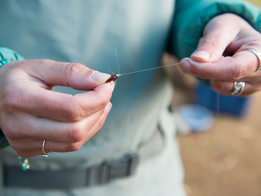 A closeup of a woman's hands holding some fly fishing line featuring a knot