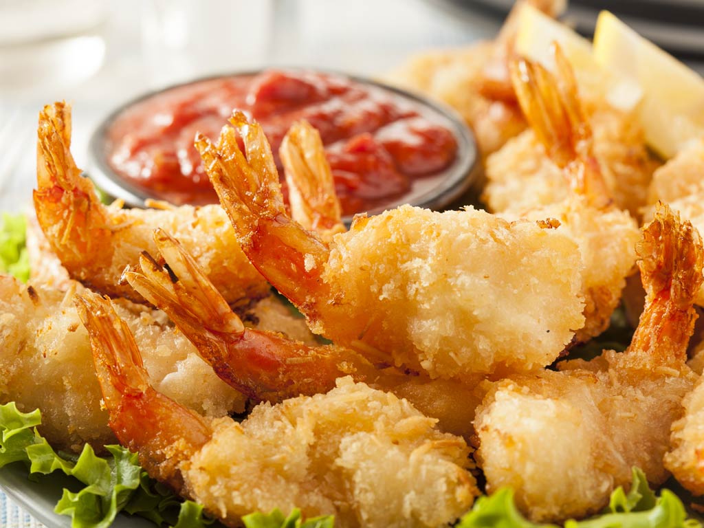 A photo featuring a plate full of deep fried shrimps served with tomato sauce, similar to what Dirty Al’s offer in their South Padre Island hook-and-cook restaurant