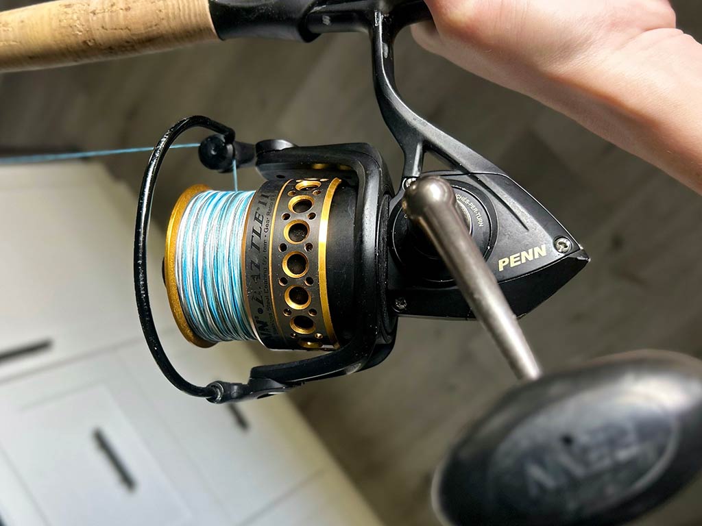 A closeup of a Penn 6000 reel being held by the rod above it, ready for saltwater fishing