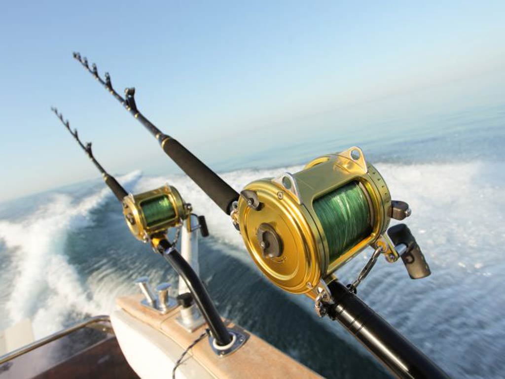 A photo of two heavy tackle trolling fishing rods on the side of a fast-moving boat