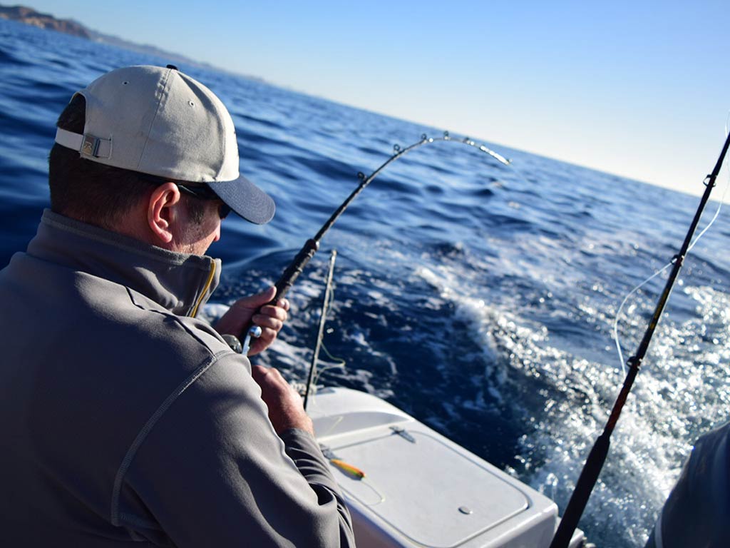 An angler struggling to reel in a big fish on a fishing charter in Latin America on a sunny day