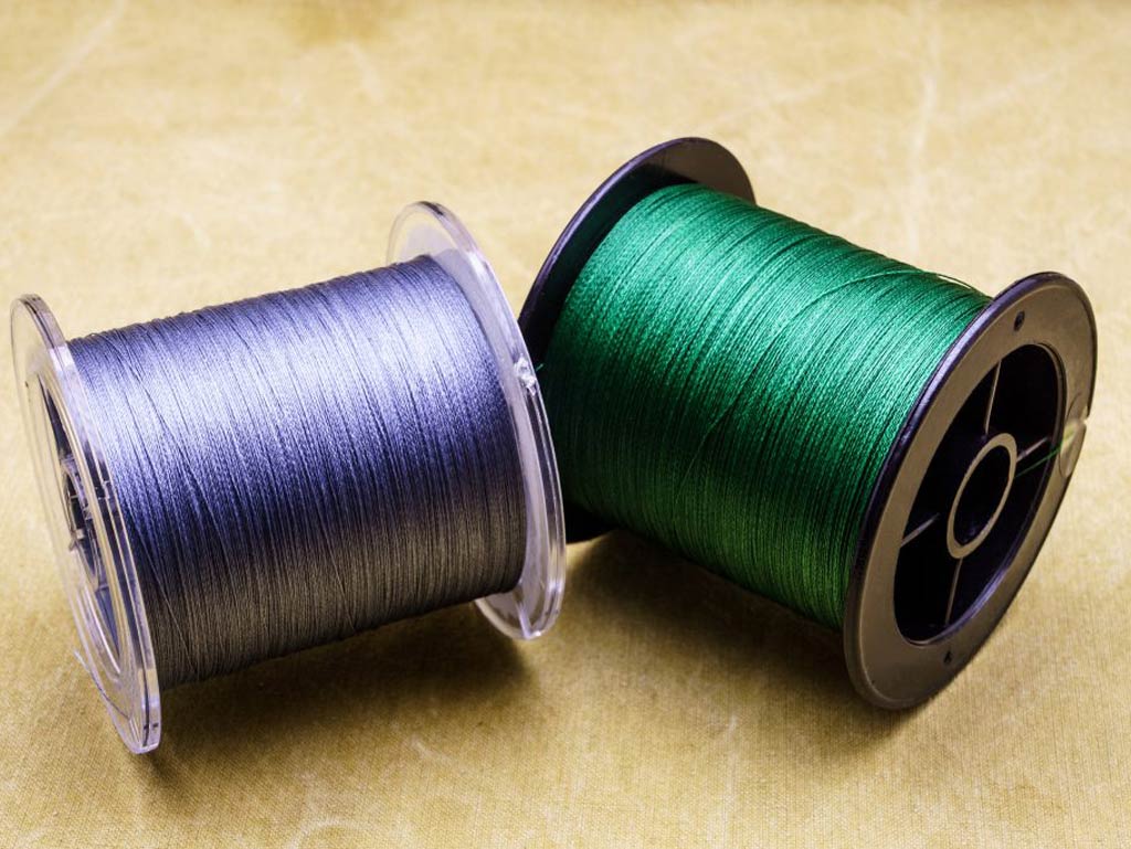 Two spools of braided fishing line, one purple and one green