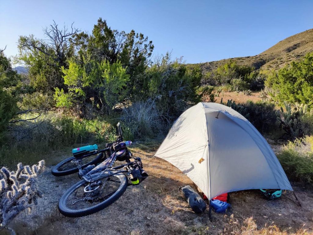 Bikepacking bike and small tent in scrubby desert landscape