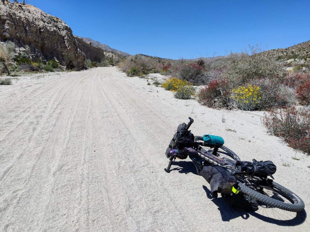 Bikepacking bike lying on sandy desert road in Fish Creek Wash