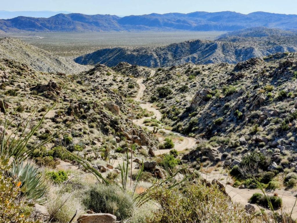 Expansive view of winding dirt road through rugged desert landscape