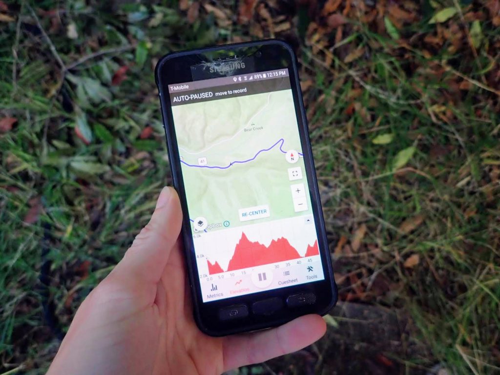 Hand holding a smartphone with RideWithGPS navigation app on the screen