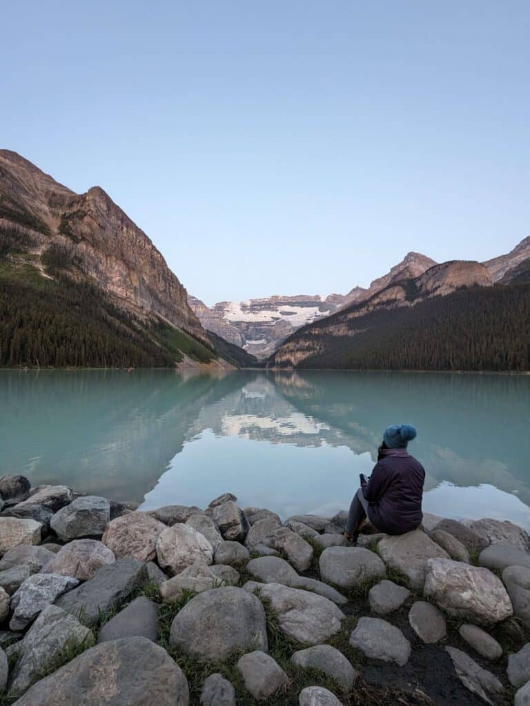 Woman sitting on stones at the shores of Lake Louise in Banff National Park