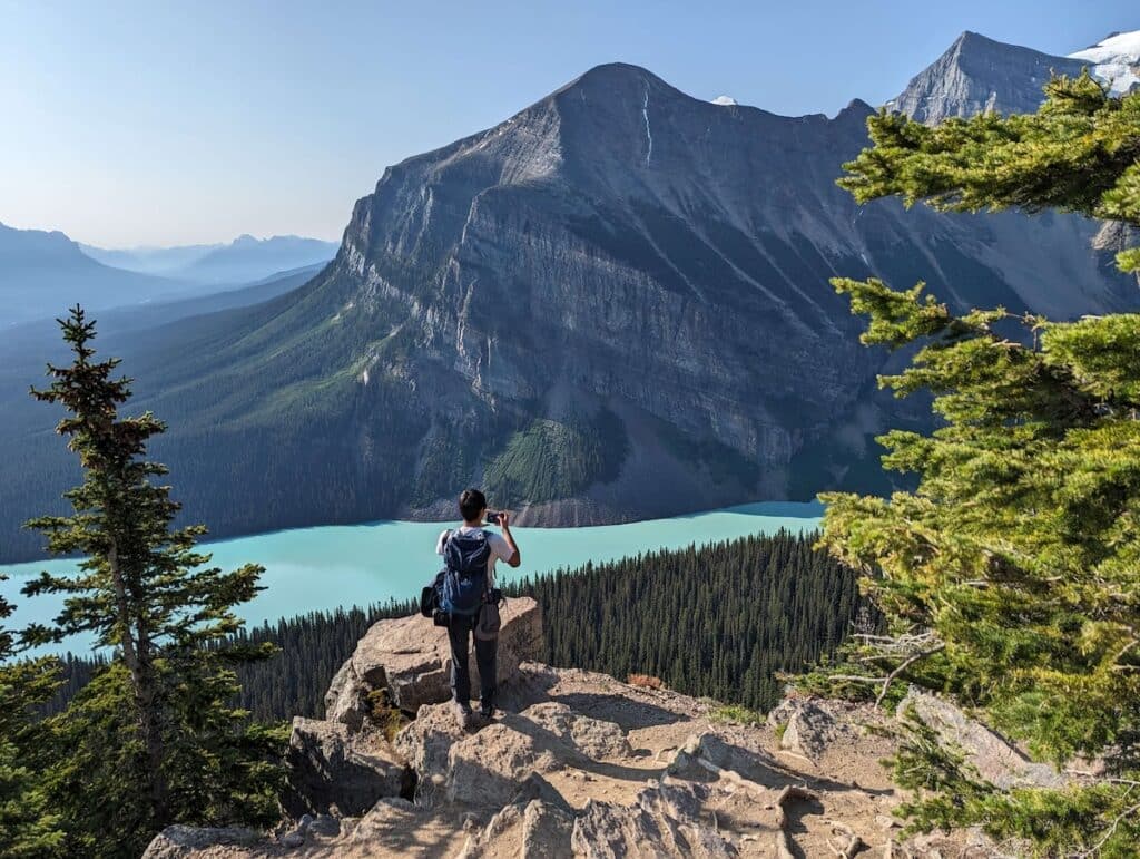 Hiker standing at spectacular lookout over turquoise-colored lake and mountains in Banff National Park