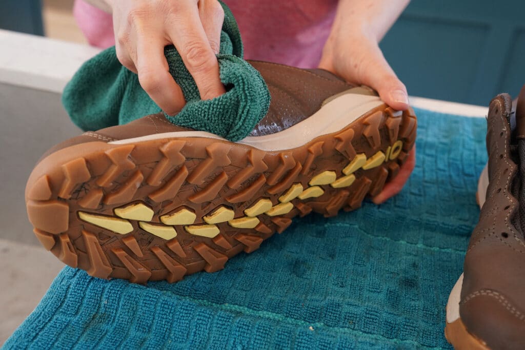 woman cleaning hiking boot with microfiber cloth