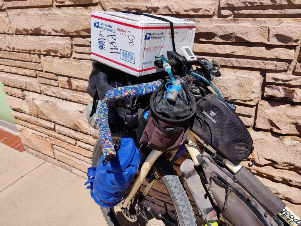 Cardboard box strapped to handlebars of bikepacking bike