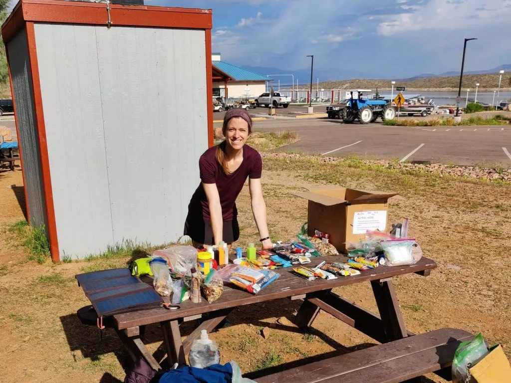 Backpacker unpacks a resupply box on a picnic table