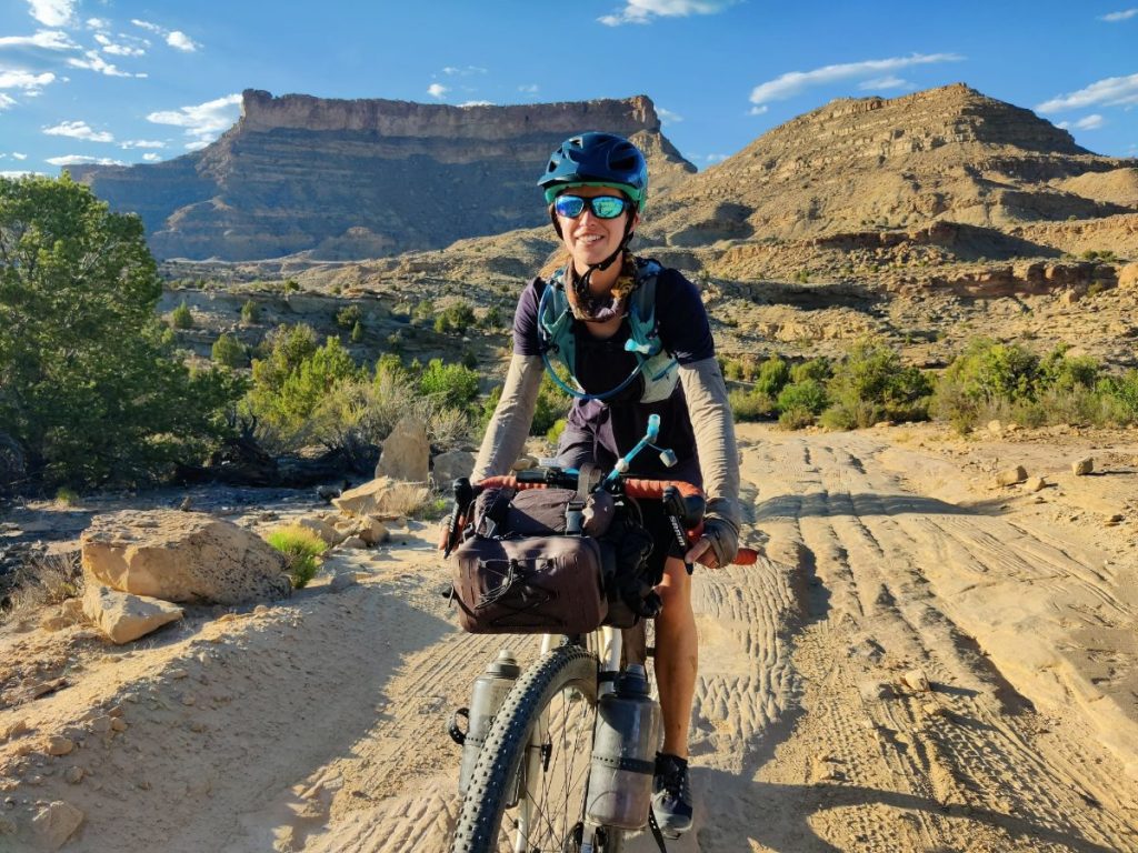Woman bikepacking on rocky desert road with drop bar bicycle