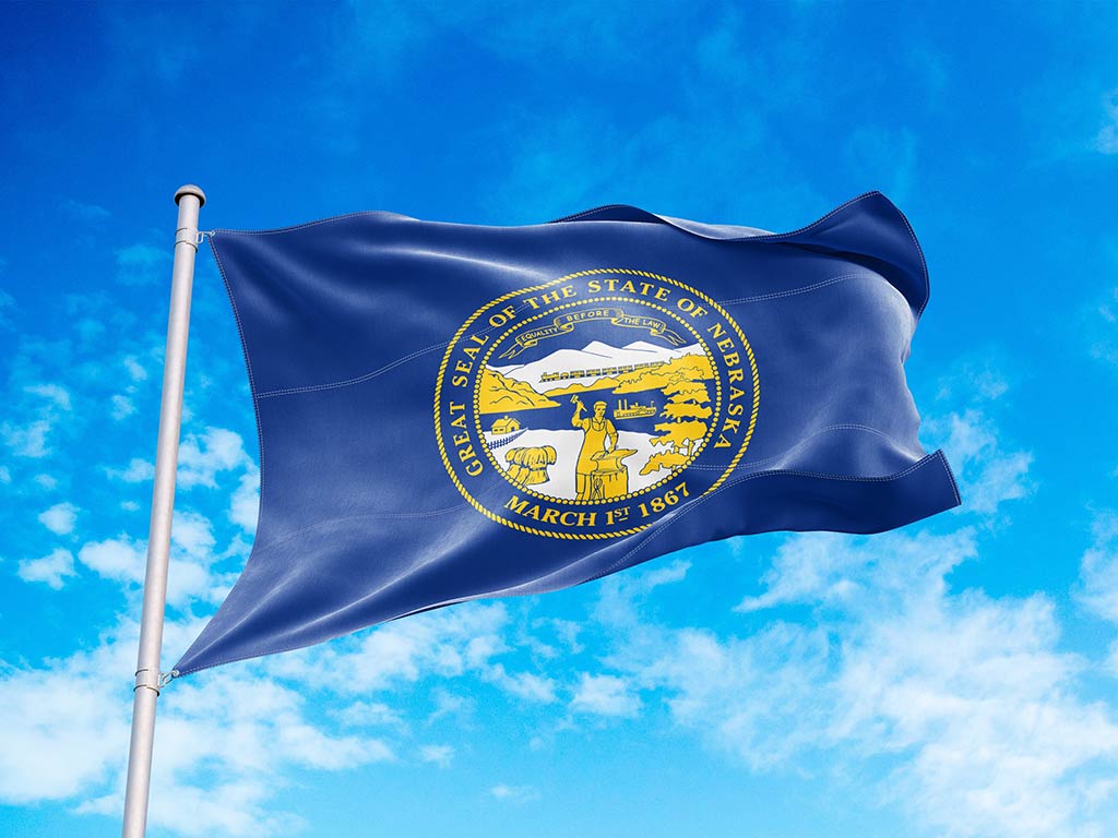 The flag of Nebraska flying from a flagpole against a background of a clear blue sky