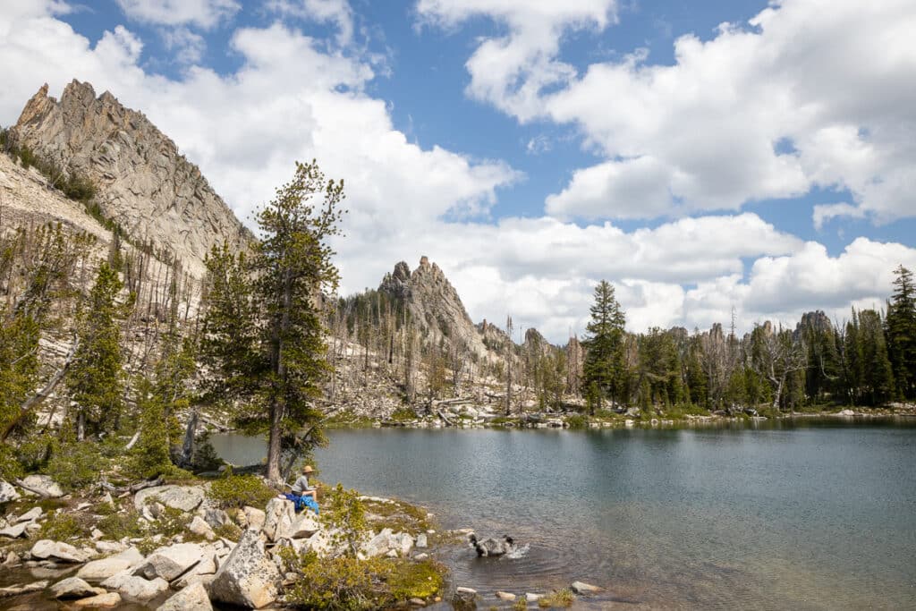 Kristen Bor sitting on the edge on a mountain lake in Idaho's Bighorn Crag Wilderness