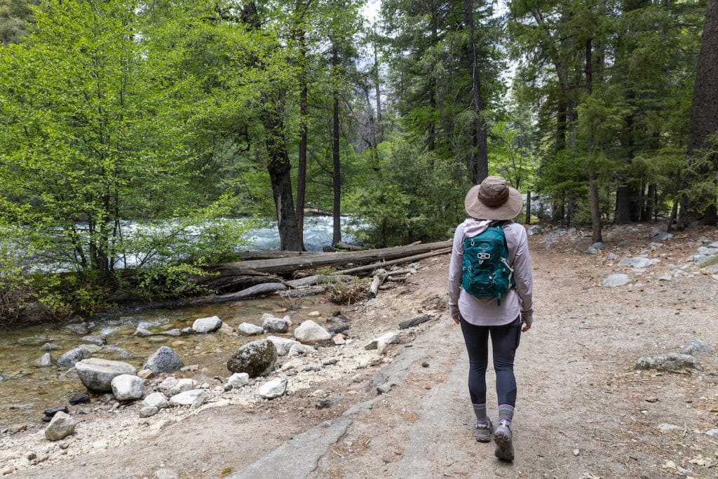 Woman hiking next to a stream in the Forest on Yosemite's Mirror lake Trail