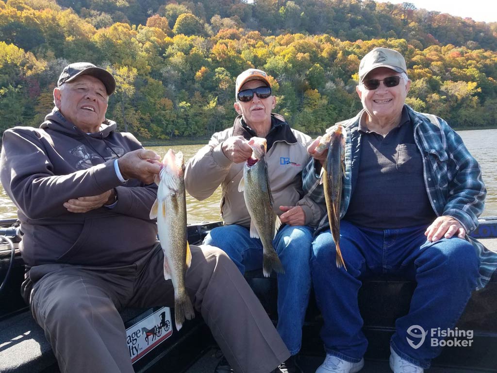 A photo featuring three elderly anglers sitting on a charter boat and posing with a Walleye each during their Memorial Day fishing trip in Lake City