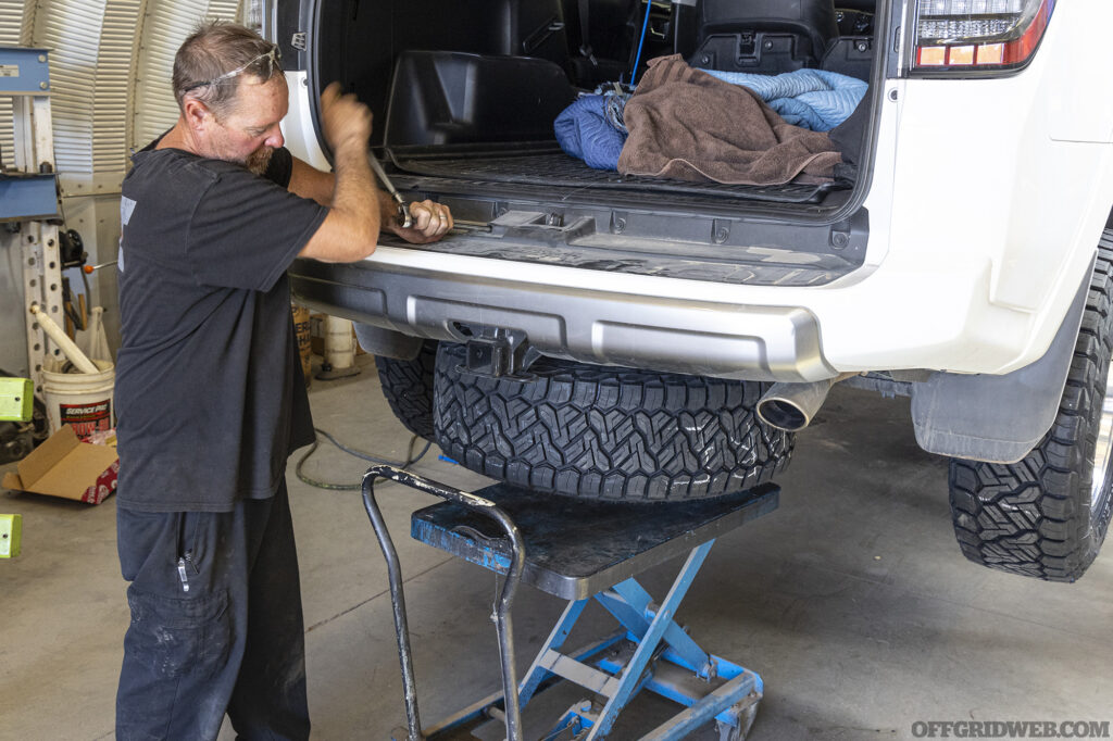 Overland 4runner raised on a lift while a mechanic works on the rear of the vehicle.