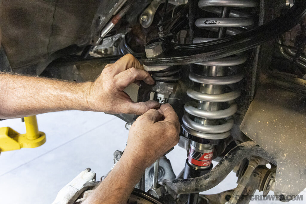 Two hands installing a suspension part on an overland 4runner.