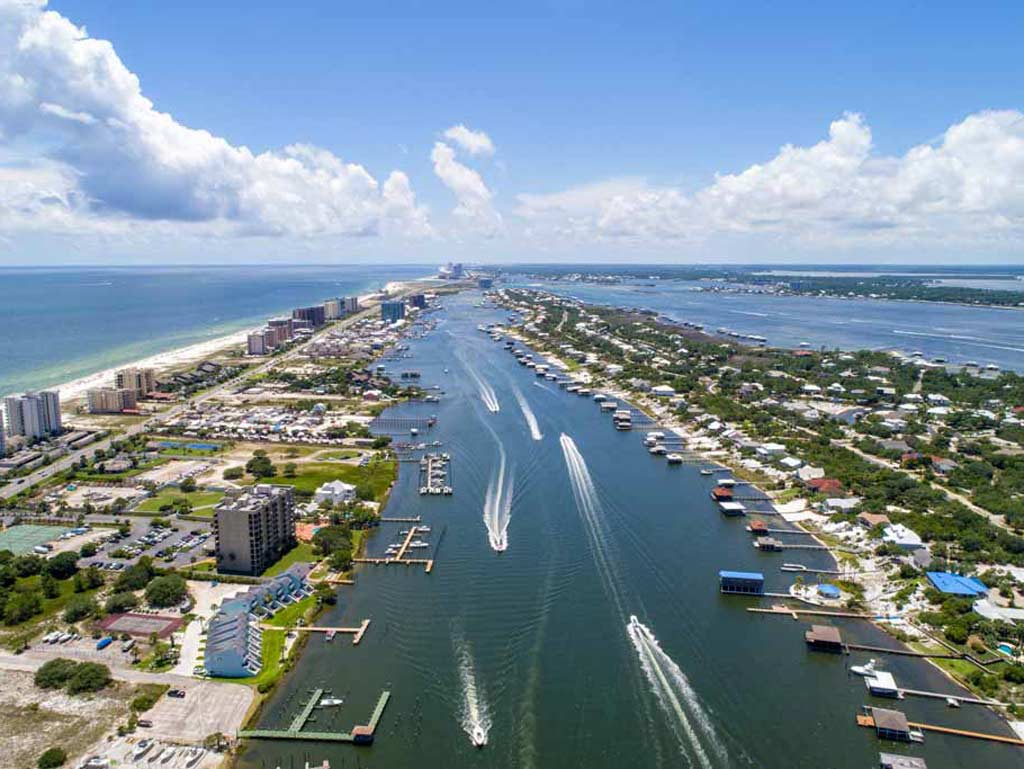 An aerial view of Orange Beach and Perdido Pass, with several boats passing through the channel.