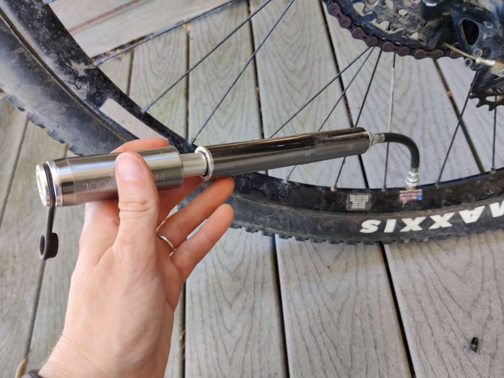 Mini pump with flexible hose attached to a bicycle wheel