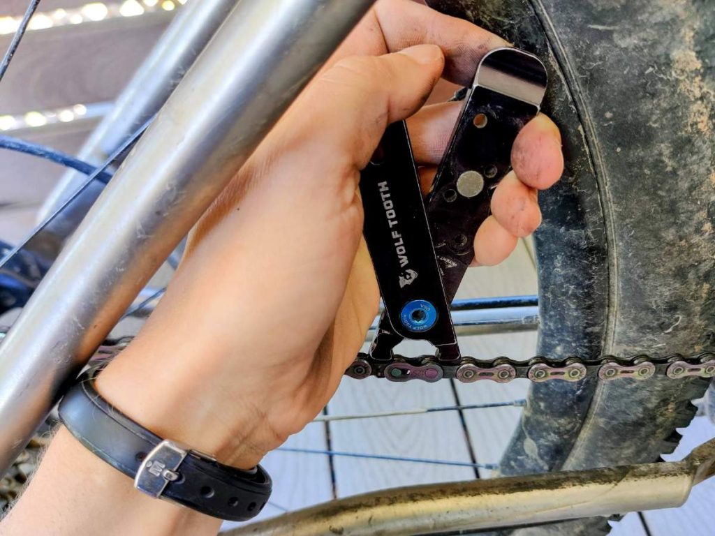 Close up of hand using Wolf Tooth quick link pliers to open a quick link on a bicycle chain