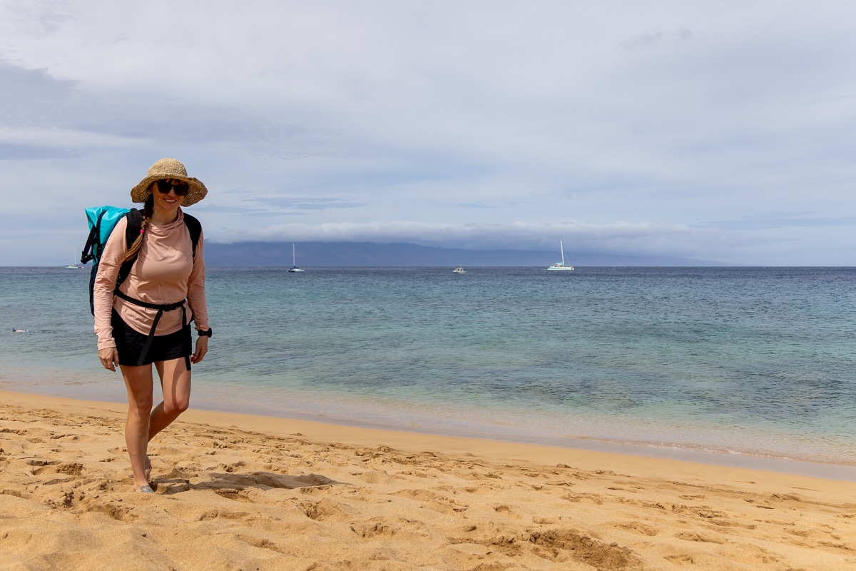 Kristen Bor walking on the beach in Maui wearing the REI Sahara Sun shirt in pink
