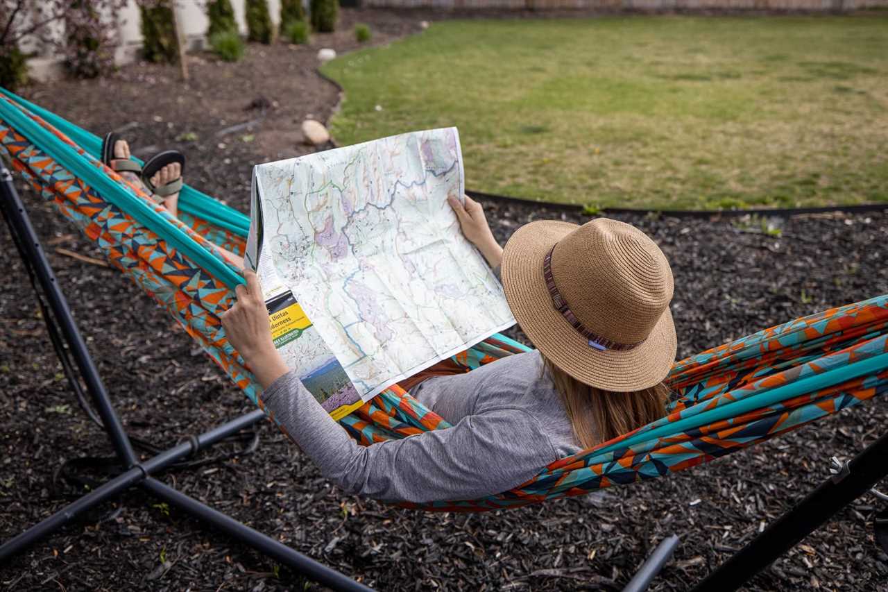 Kristen Bor lays in a printed ENO doublenest hammock looking at a map