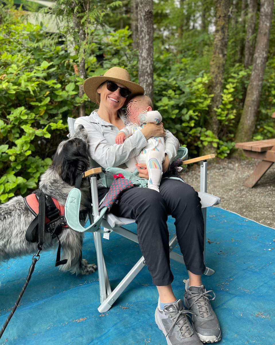 Kristen Bor sitting in a Dometic Go camping chair holding her baby at a campsite