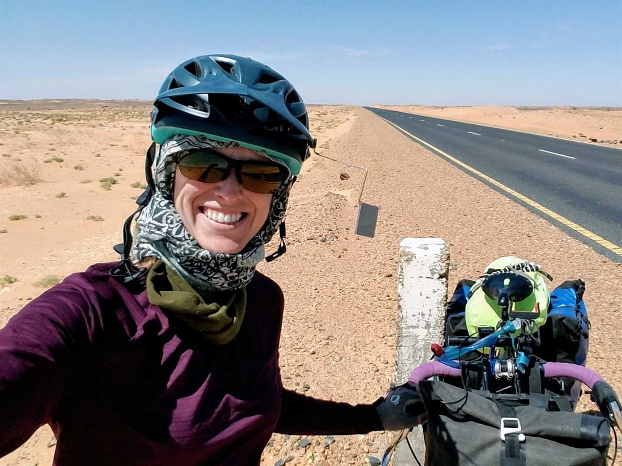 Woman with touring bike and helmet mirror on desert road