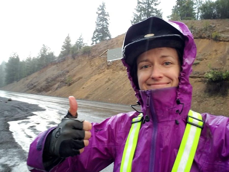 Cyclist in the rain wearing purple jacket and helmet mirror and giving thumbs up